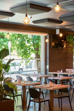 Vista interna della Pizzeria Luna Rossa con elementi verdi e illuminazione calda, intervento acustico curato da 2B Resine.